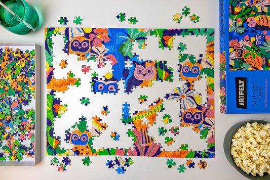 Artfelt's-Midnight-Owls-jigsaw-puzzle-in progress-with-popcorn-and-a-glass-of-water